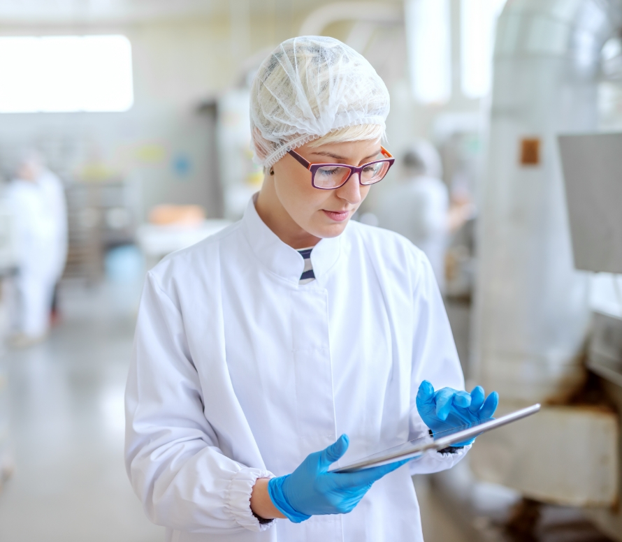 A female wearing a hair net and white coverup with blue latex gloves is reviewing the Optisolve Pathfinder and Savi app