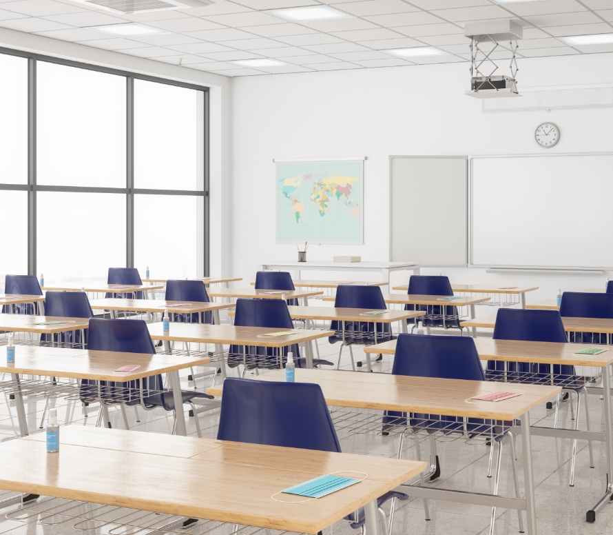 Large classroom with classroom desks and chairs, face masks on each desk and hand sanitizer