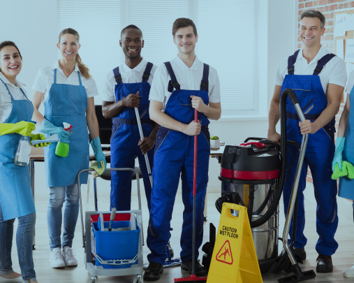 Group of janitors smiling in blue aprons holding cleaning equipment.