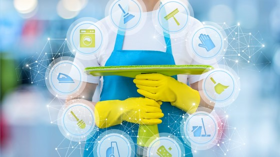 A janitor in a white shirt and bright blue apron is holding a bright green flat surface mop.