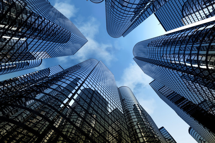 A spectacular view from the bottom of many high-rise buildings with glass windows looking up towards the sky.